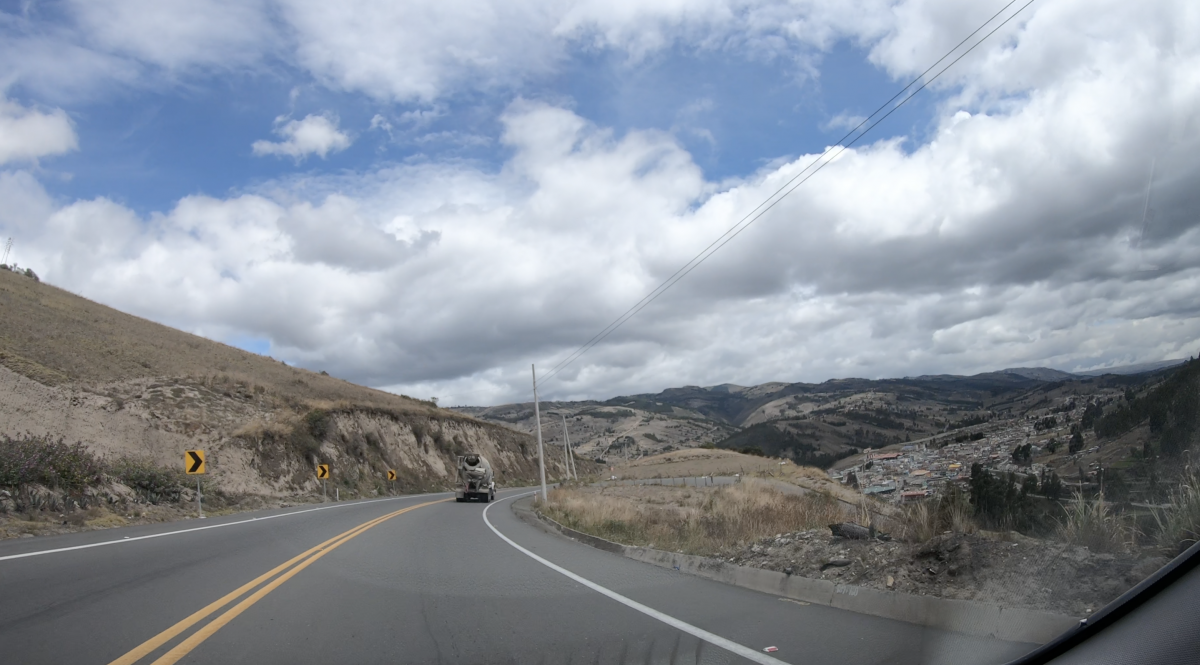 Mountain road with yellow centre lines seen through a car windshield, a truck ahead